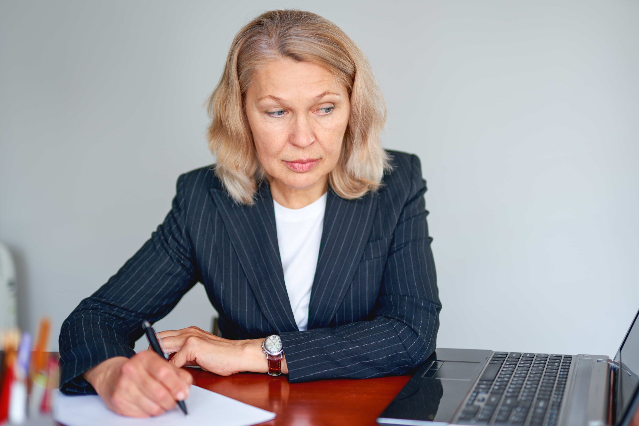 Businesswoman working at a desk in an office writing notes